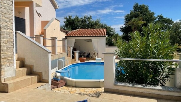 A swimming pool with a tiled deck, a covered patio area, and a staircase leading to an upper level. - Pleasant Apartment With Pool (Porec)