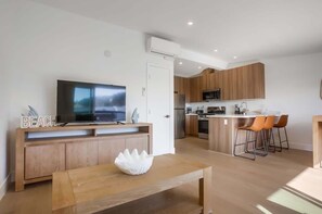 Una cocina moderna con armarios de madera, microondas integrado y una isla central con taburetes de bar.