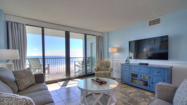 A room with a balcony, a sofa, a coffee table, a TV, and a cabinet.