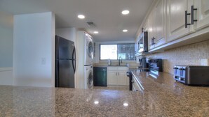 A modern kitchen with granite countertops, stainless steel appliances, and white cabinetry.