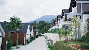 A modern residential area with a paved pathway, stone walls, and greenery. - Royal Urban Resort (Caringin)
