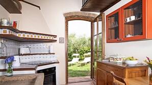 A kitchen with a tiled backsplash, a wooden countertop, a built-in oven, and a window leading to an outdoor area with chairs. - Cosy apartment with pool, A/C, WIFI, TV, patio and panoramic view, close to San Gimignano (Montauto)
