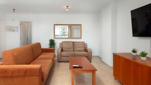 A living room with a sofa, a chair, a coffee table, and a TV.