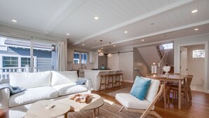 Un salon spacieux avec un canapé blanc, une table basse et un coin repas comprenant des chaises et une table en bois.