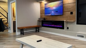 Una sala moderna con televisor de pantalla plana montado en una pared de madera, un banco y una chimenea.