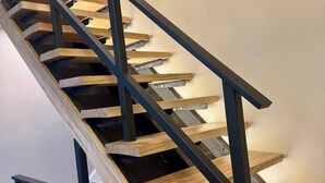 Una escalera moderna con escalones de madera y barandillas de metal negro.
