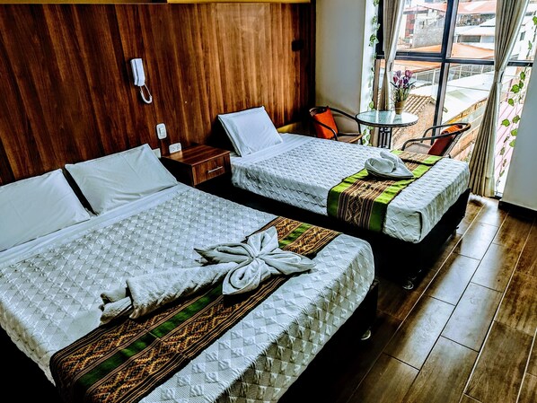 A hotel room with two beds, a small table, a chair, and a view of the city through large windows. - Velvet Residence Cusco (Cusco)