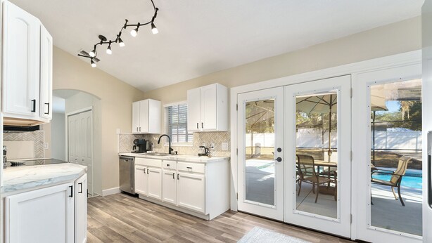 A modern kitchen with white cabinets, a marble countertop, and a built-in dishwasher. - Vacation Home in Lady Lake (Lady Lake)