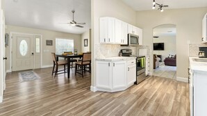 A modern kitchen with white cabinets, a microwave, and a dining area with a table and chairs. - Vacation Home in Lady Lake (Lady Lake)