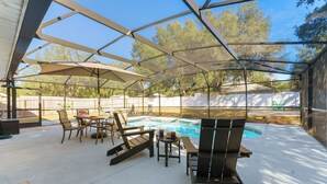 A covered outdoor area with a pool, seating, and a table. - Vacation Home in Lady Lake (Lady Lake)