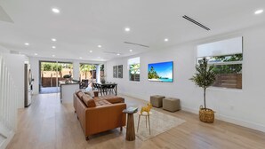 A spacious living area with a brown sofa, a coffee table, and a dining area in the background. - Up to 12 guest Modern Villa near Wynwood! (Miami)