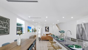 A modern kitchen with a dining area, featuring a wooden table, chairs, and a bar area with stools. - Up to 12 guest Modern Villa near Wynwood! (Miami)