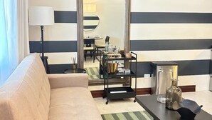Een woonkamer met een bank, een salontafel, een lamp, een spiegel en een plafondventilator.
