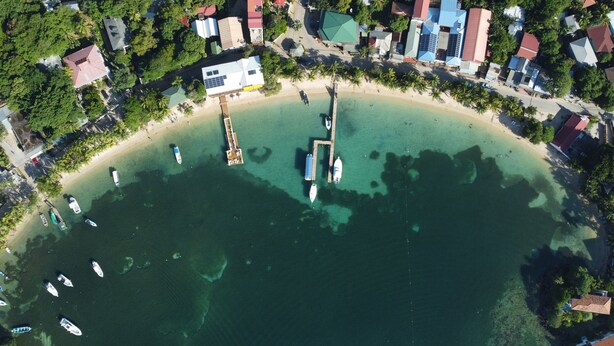 Eine Luftaufnahme einer Küstenregion mit Strand, Booten und Gebäuden.