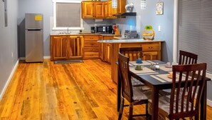 Eine moderne Küche mit Holzausstattung, einem Edelstahlkühlschrank und einem Essbereich mit Tisch und Stühlen.