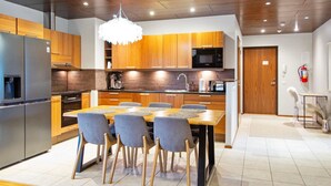 Una cocina moderna con armarios de madera, un refrigerador de acero inoxidable y un comedor con mesa y sillas.