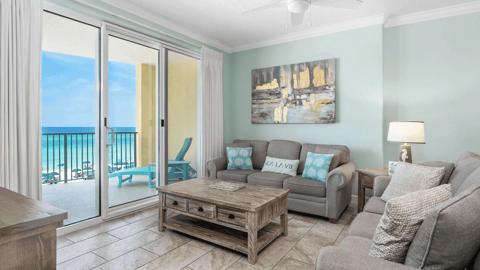 A living room with a sofa, coffee table, and a view of the beach through a sliding door.