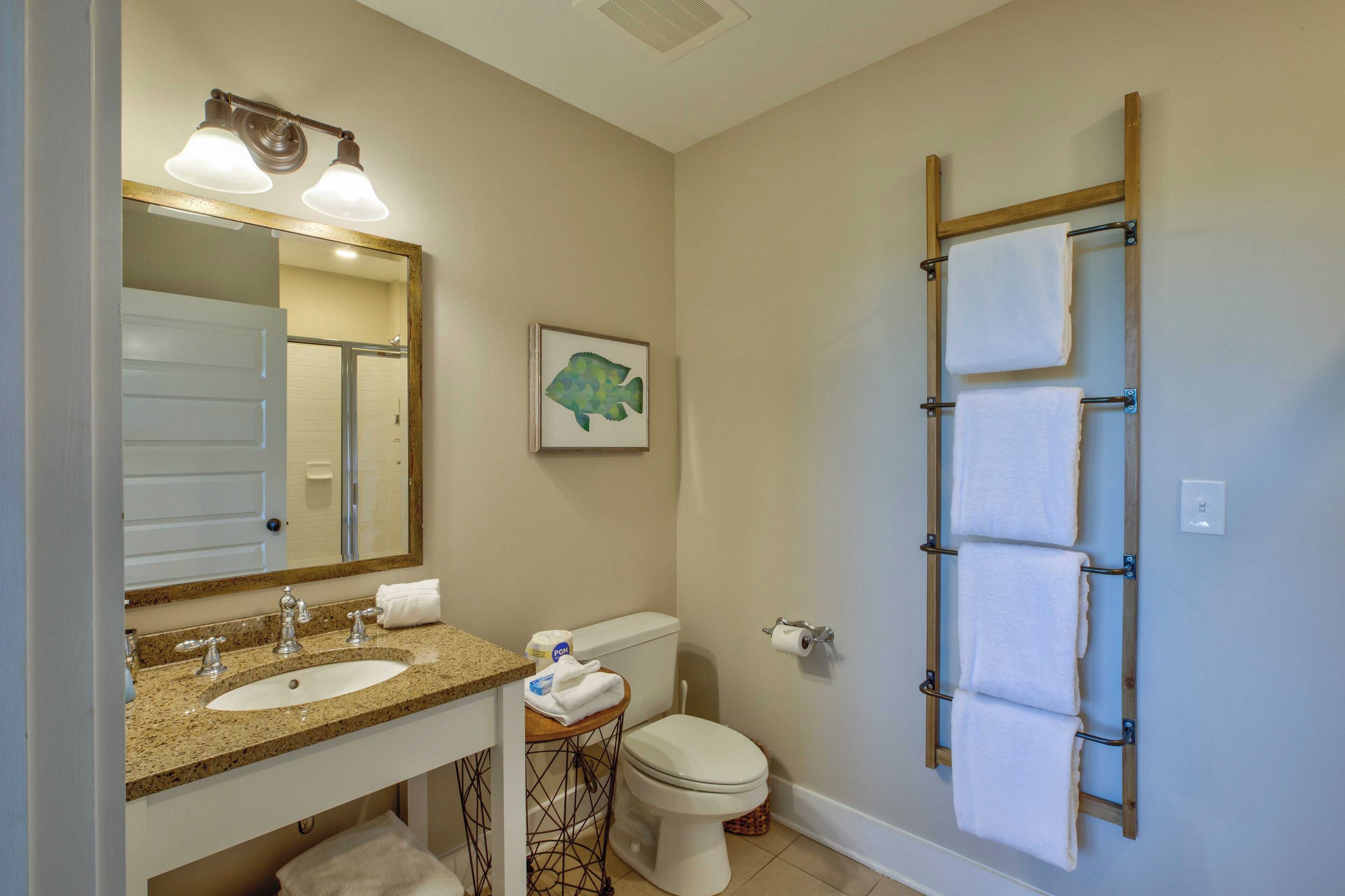 A bathroom with a sink, mirror, toilet, and towel rack.