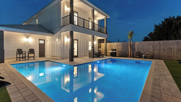 A two-story house with a swimming pool, outdoor seating, and a wooden fence. - Wanderlust by Avantstay Walk to Beach + Pool New Construction (Panama City Beach)