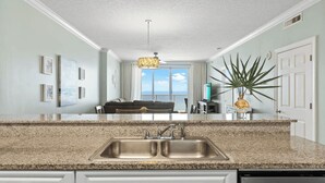 Cocina con encimeras de granito, un lavamanos doble y vistas al exterior.