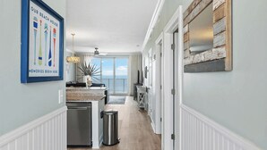 Un pasillo con un área de cocina, un basurero y una puerta que da a un balcón.