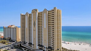 Un hotel de gran altura con varios balcones, vista al mar y un cielo despejado.
