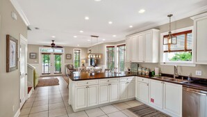 A spacious kitchen with white cabinetry, a central island, and a view to the outside. - 5min Walk to Beach Private Pool, Rooftop Deck A Piece of Heaven by Avantstay (Santa Rosa Beach)