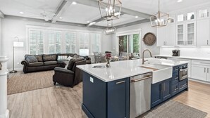 A modern kitchen with a central island, white cabinetry, and pendant lighting. - Cabana Blue by Avantstay Walk to Beach, Golf Cart+bikes Included Pool Access (Santa Rosa Beach)