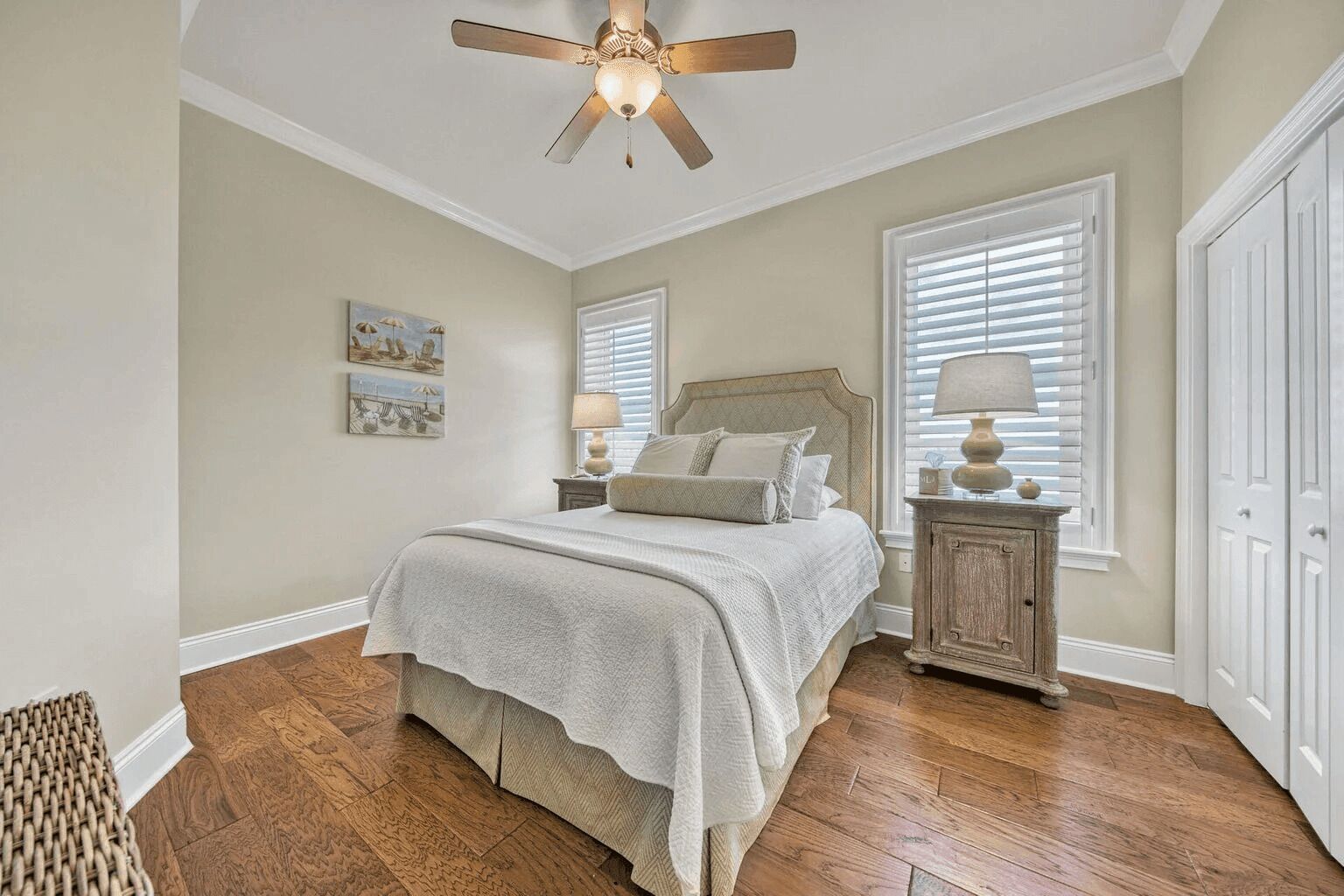 A bedroom with a bed, a nightstand, a ceiling fan, and a window with blinds.