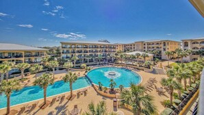 Ein Resort mit einem zentralen Pool, mehreren Balkonen und Palmen.