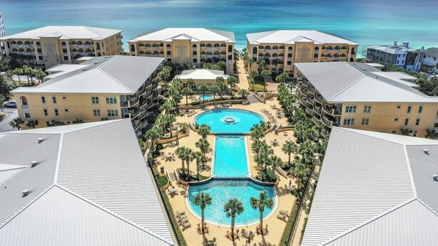 Ein Resort mit einem zentralen Pool, mehreren Gebäuden und Blick auf den Ozean.