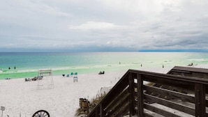 A beach with a wooden deck, lounge chairs, and a sign indicating a beach area. - Shellom by Avantstay Newly Built, Pool Access (Santa Rosa Beach)