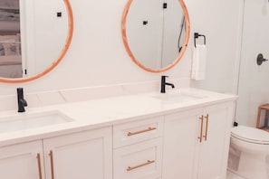 Een moderne badkamer met twee wasbakken, een zwarte kraan en een toilet.