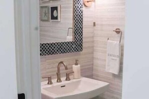 A bathroom with a sink, two faucets, a mirror with a decorative frame, and a towel hanging on a rack. - Shellom by Avantstay Newly Built, Pool Access (Santa Rosa Beach)