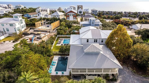 A large house with a swimming pool, surrounded by other houses and a view of the ocean. - Porch Paradise by Avantstay Private Pool Seacrest (Panama City Beach)