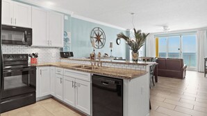 A kitchen with white cabinets, a black microwave, and a dishwasher. - Emerald Isle 701 by Avantstay Gul Front Corner Unit 2 Pools (Panama City Beach)