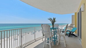 A balcony with a view of the beach, white chairs, a table, and a potted plant. - Emerald Isle 701 by Avantstay Gul Front Corner Unit 2 Pools (Panama City Beach)
