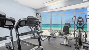 A gym with Nautilus equipment, a bench, and a view of the beach. - Emerald Isle 701 by Avantstay Gul Front Corner Unit 2 Pools (Panama City Beach)