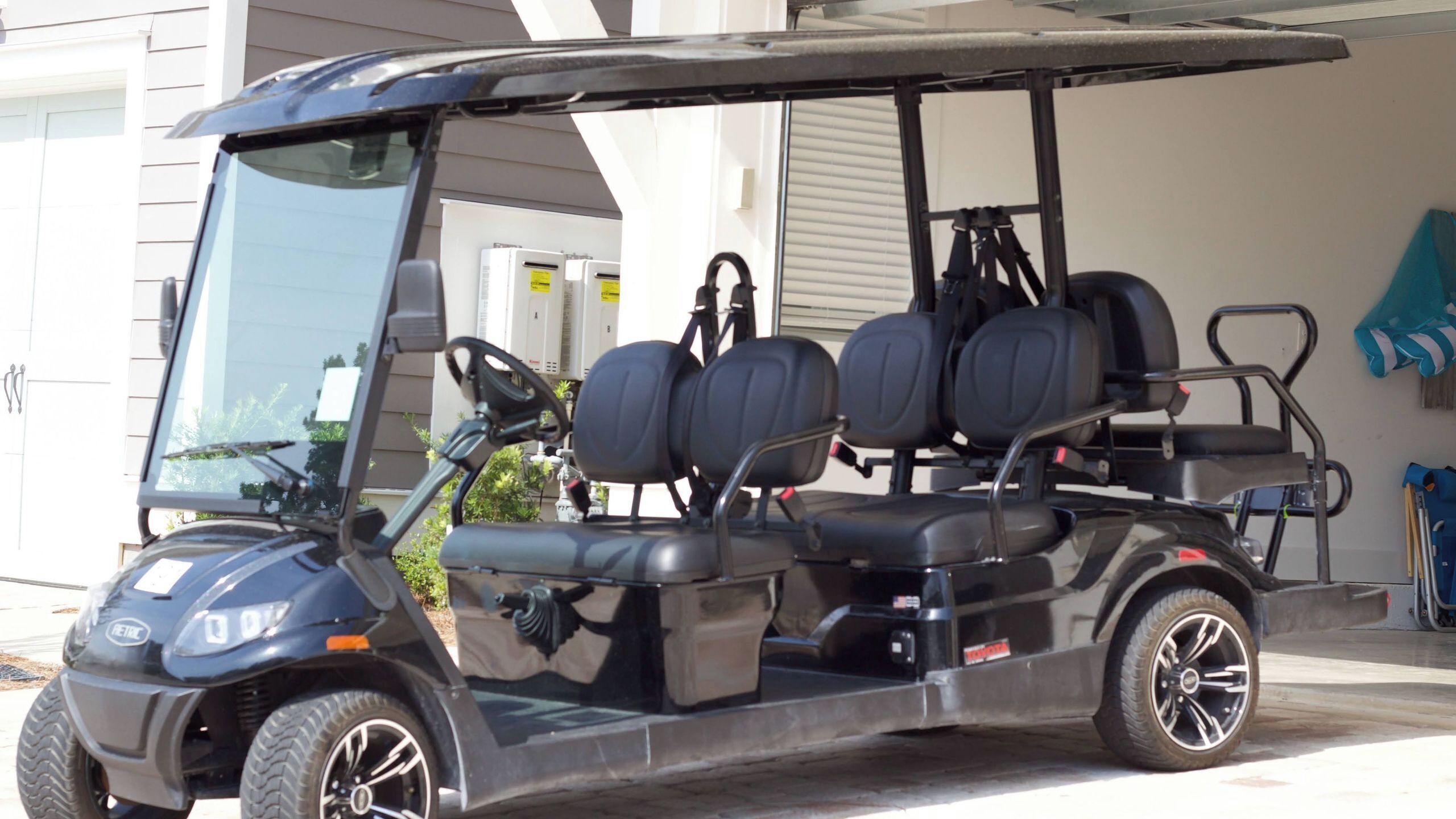 Un carrito de golf con asiento para el conductor y tres asientos para pasajeros, estacionado frente a un edificio.