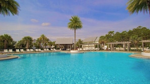 A large outdoor swimming pool with lounge chairs and palm trees.
