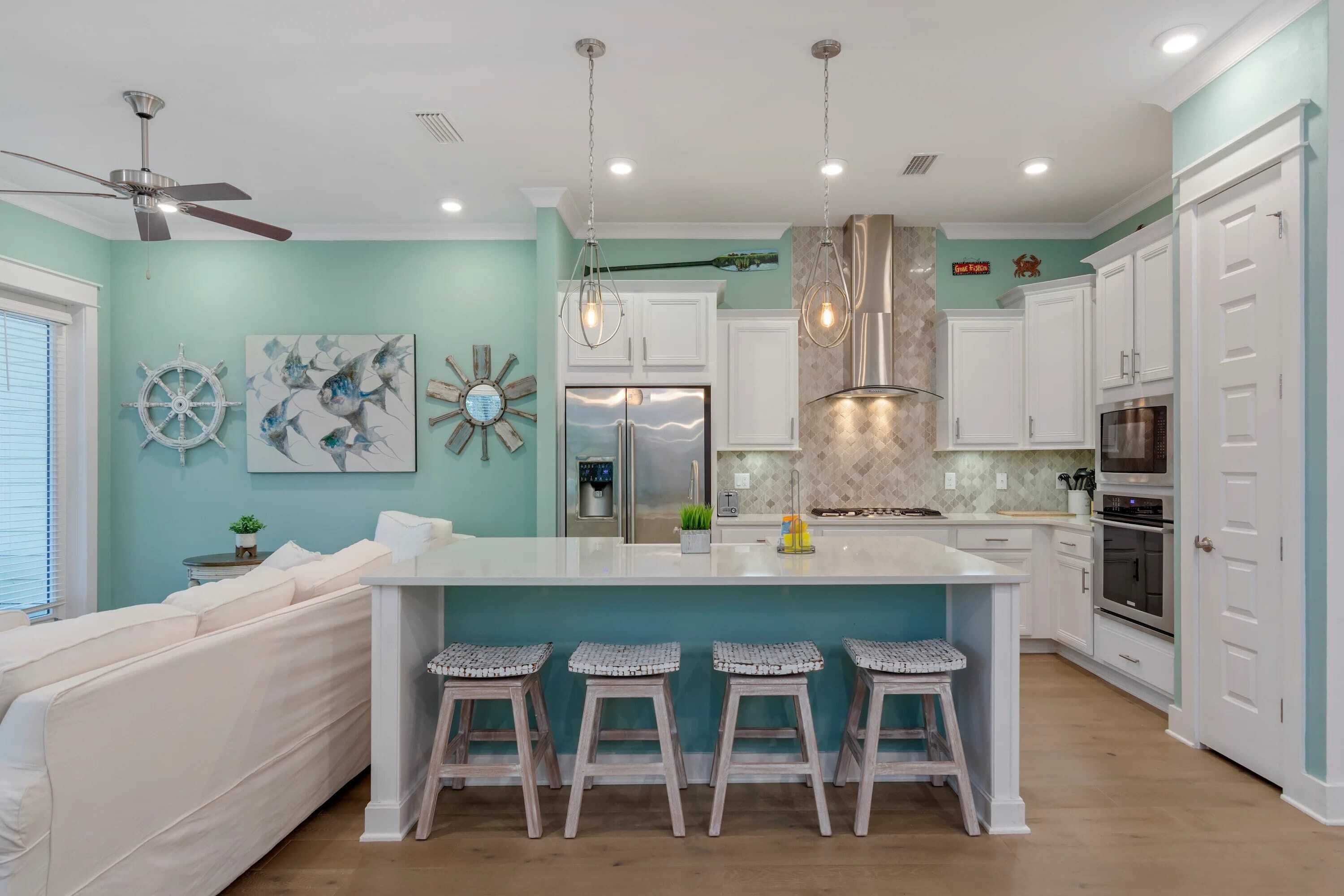 A modern kitchen with a central island, white cabinetry, and a ceiling fan.