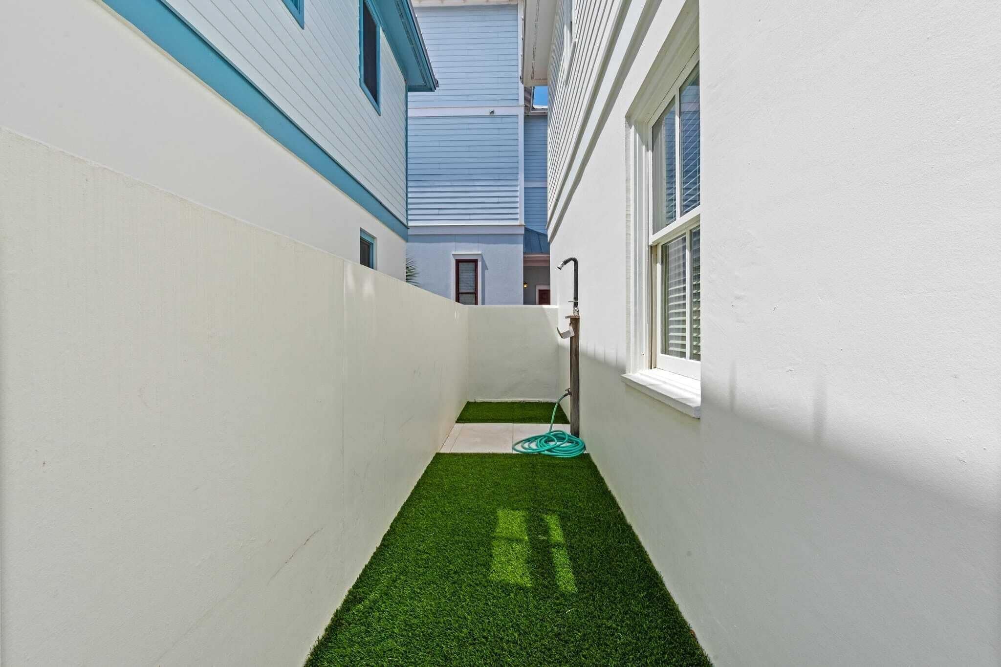 A narrow corridor with white walls and a small patch of artificial green grass.