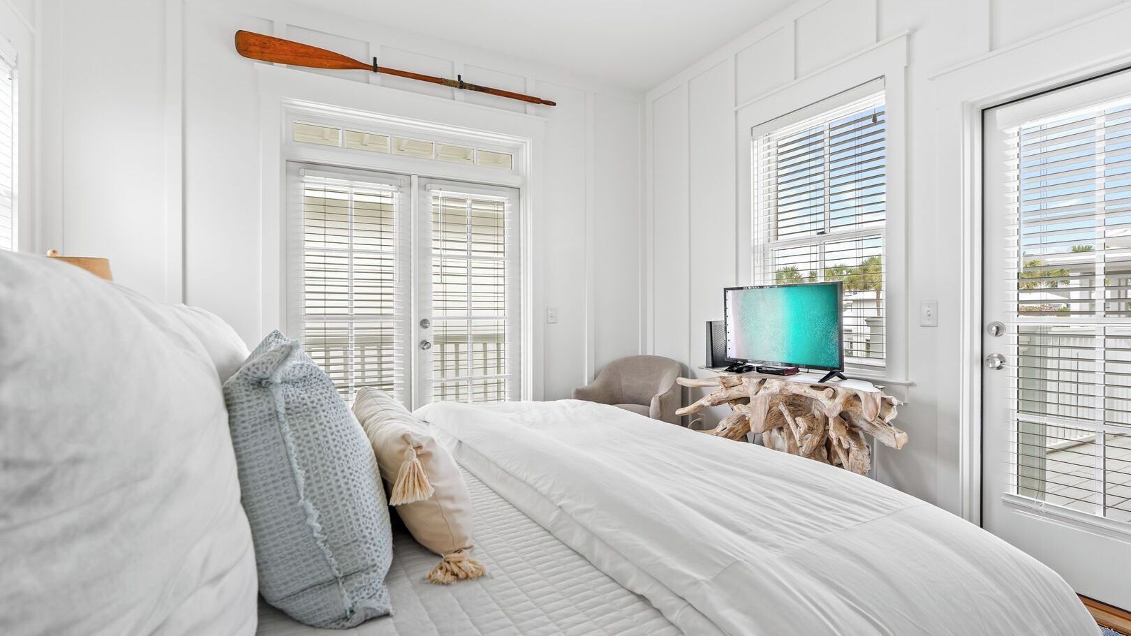 A bedroom with a bed, a television, a chair, and a wooden side table.