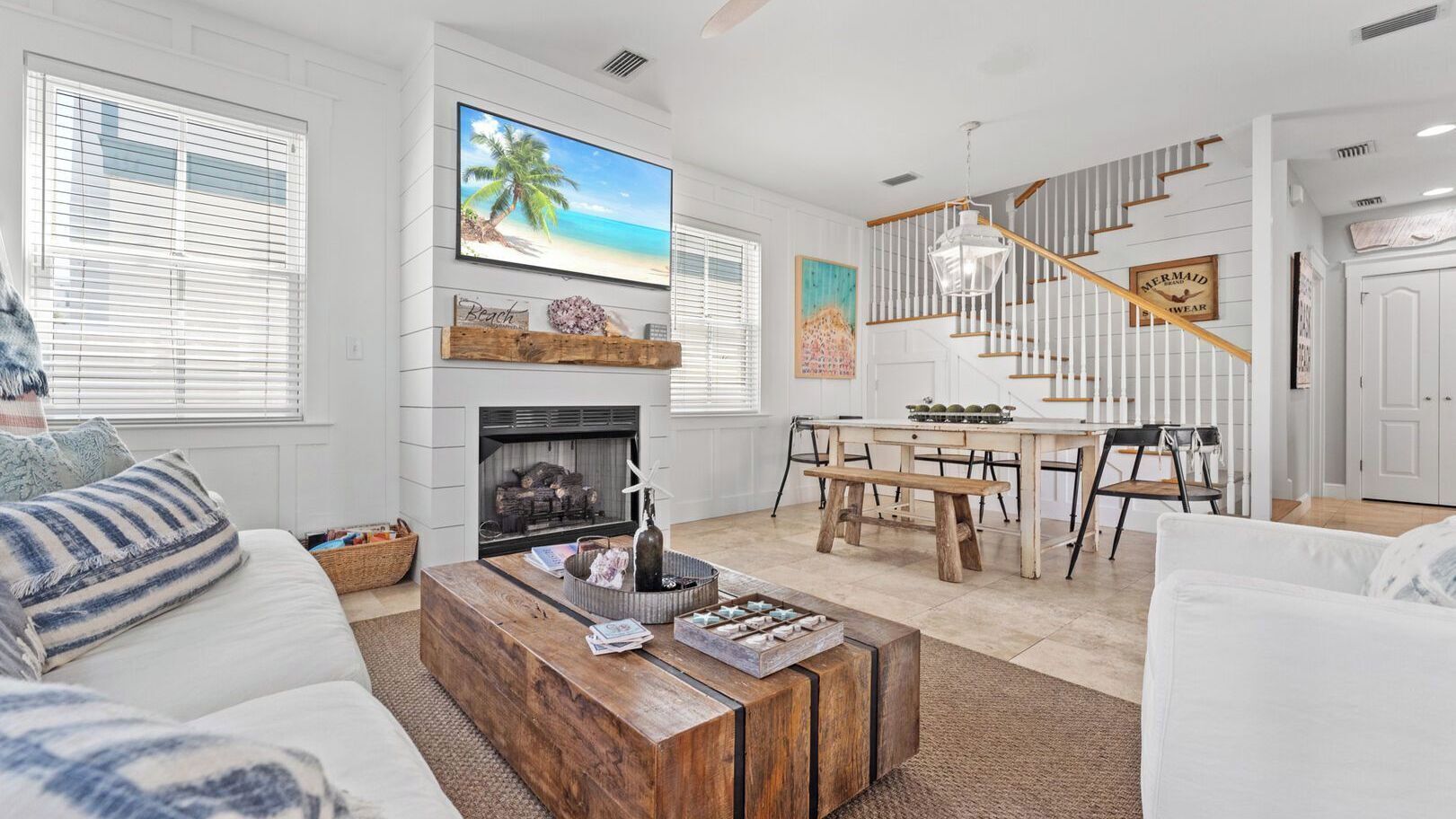 A spacious living room with a fireplace, a dining area, and a staircase.