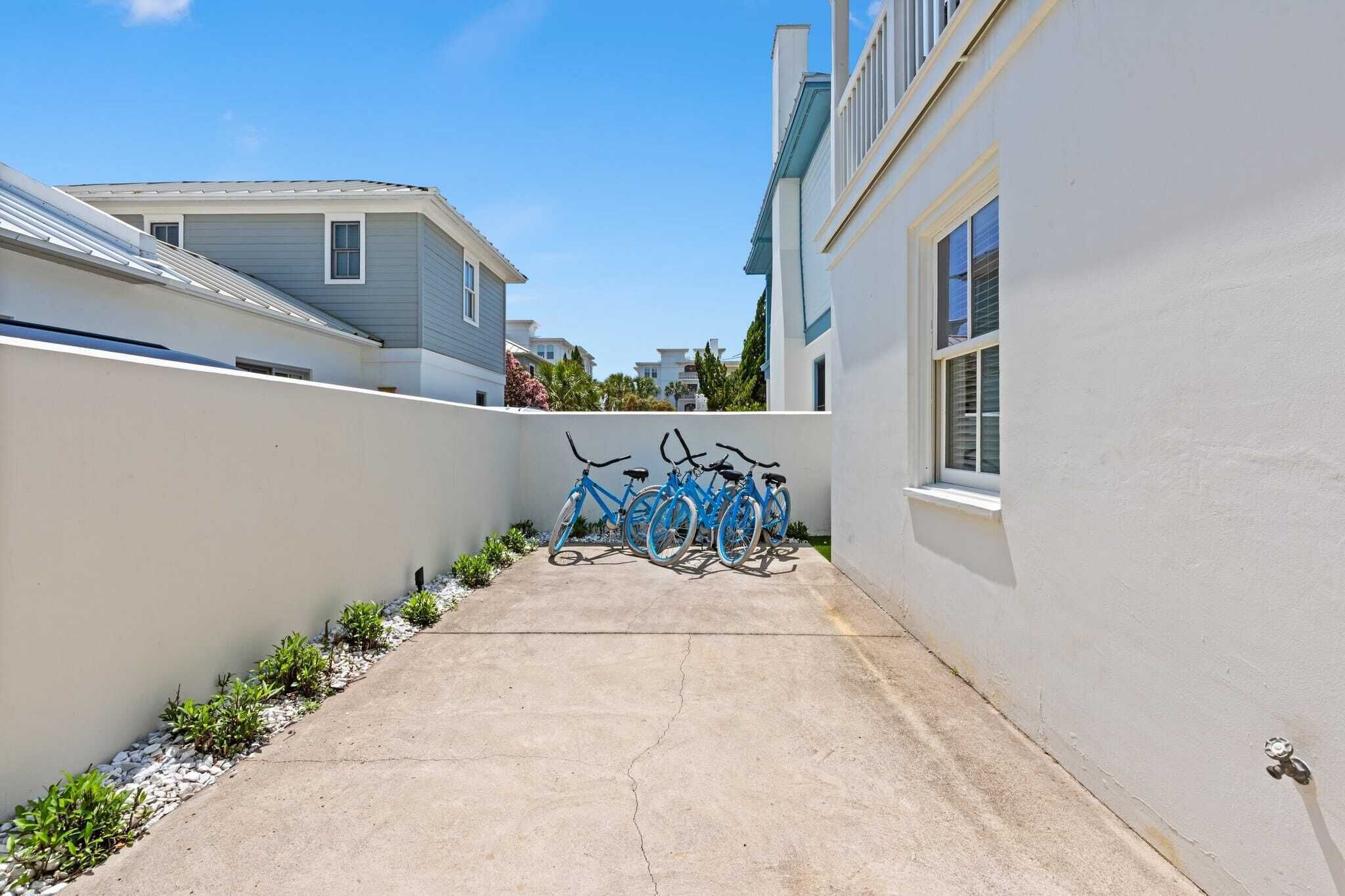 A narrow concrete pathway with bicycles parked on the right, surrounded by white walls and a clear blue sky.