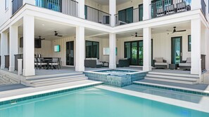 Une maison à deux étages avec une piscine, un espace salon extérieur et un jacuzzi.