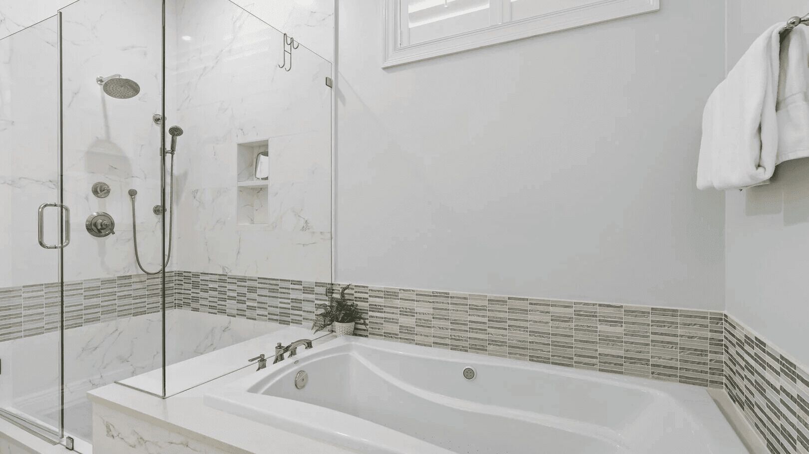 Une salle de bain moderne dotée d’une douche à parois de verre, d’une baignoire sur pieds et d’un mur recouvert de carreaux.
