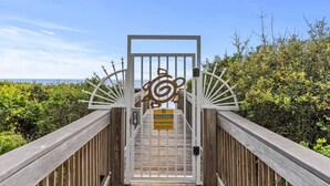 Une promenade en bois mène à une entrée fermée par un portail, sur laquelle est apposée une pancarte indiquant qu’il s’agit d’une propriété privée et que l’accès est interdit.