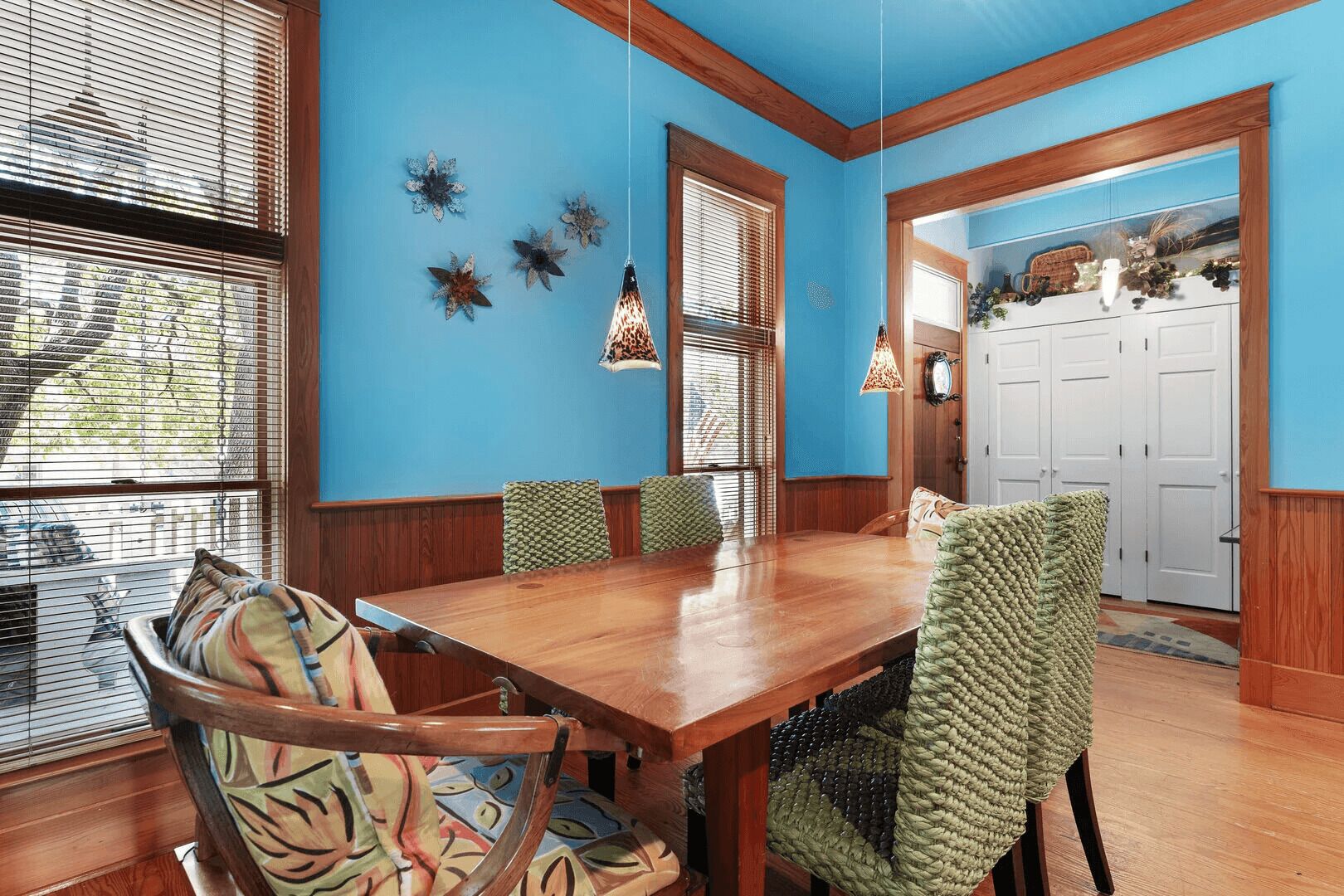 A dining room with a wooden table and chairs, blue walls, and decorative wall art.
