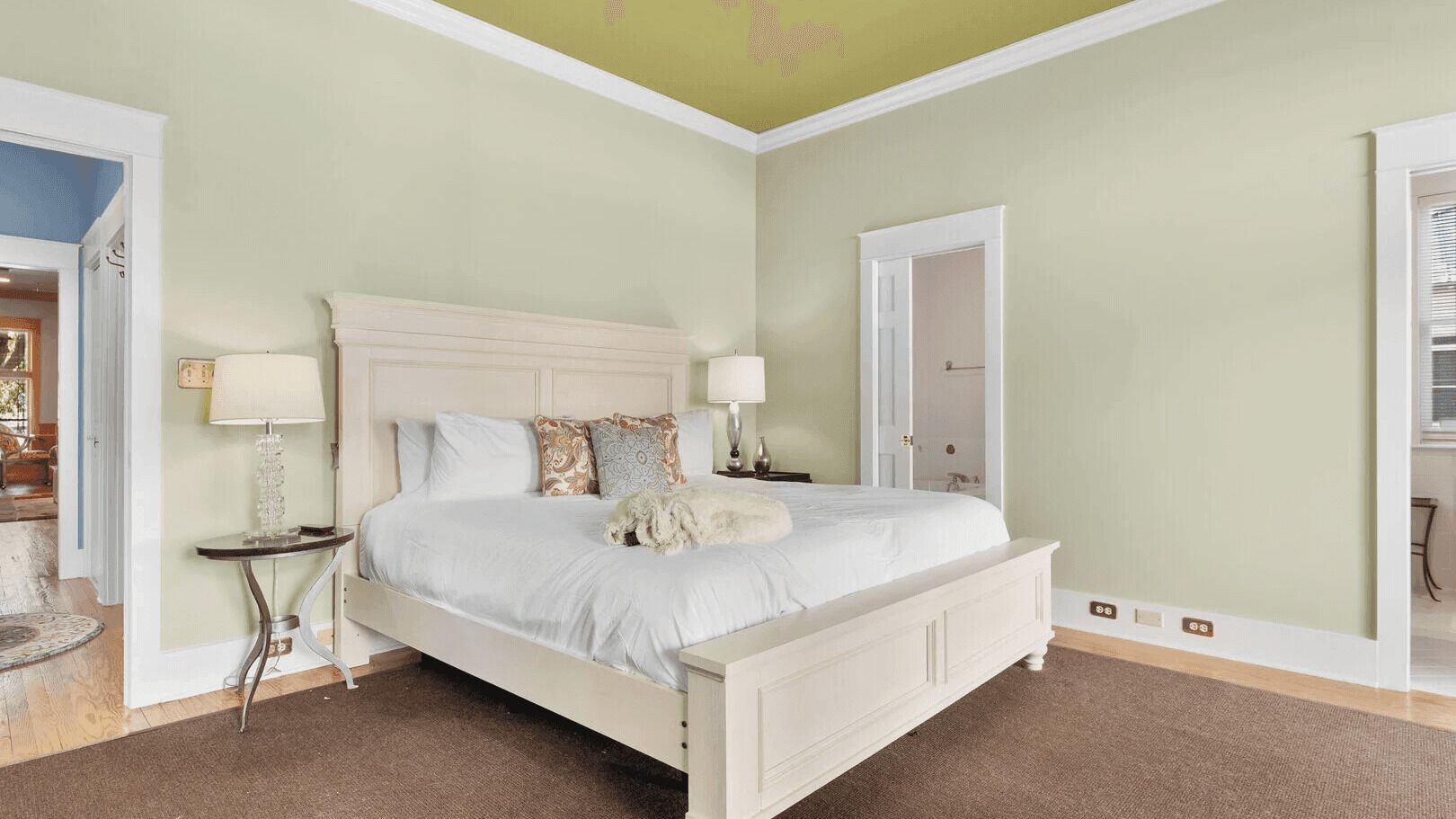 Een slaapkamer met een bed, nachtkastjes, een lamp en een deur.
